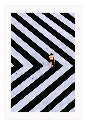 An urban wall art with an aerial view of a lady walking on black and white street crossing stripes