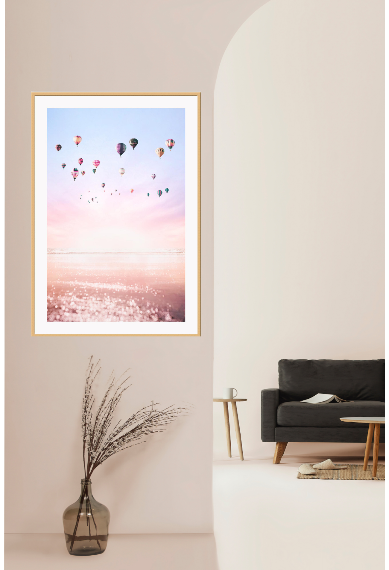 A framed print of multiple hot air balloons floating in a pink and purple sky, with a smooth matte wood finish frame. Displayed on cream wall.