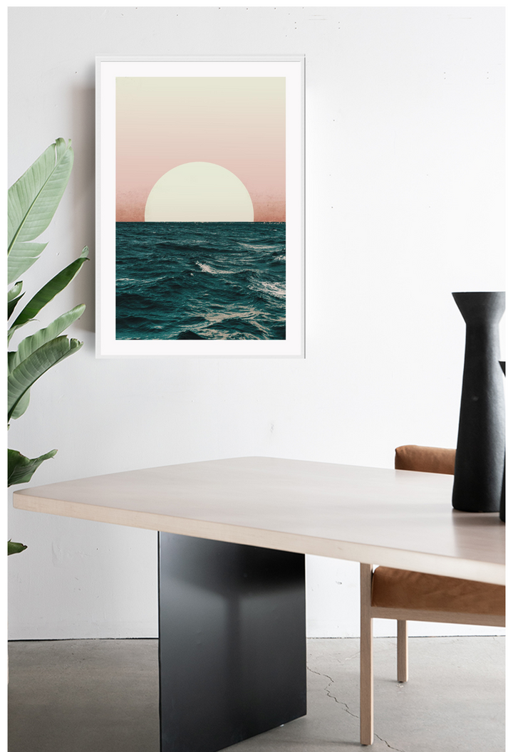 Setting sun on horizon of the ocean with orange to pink sky and rough dark blue sea