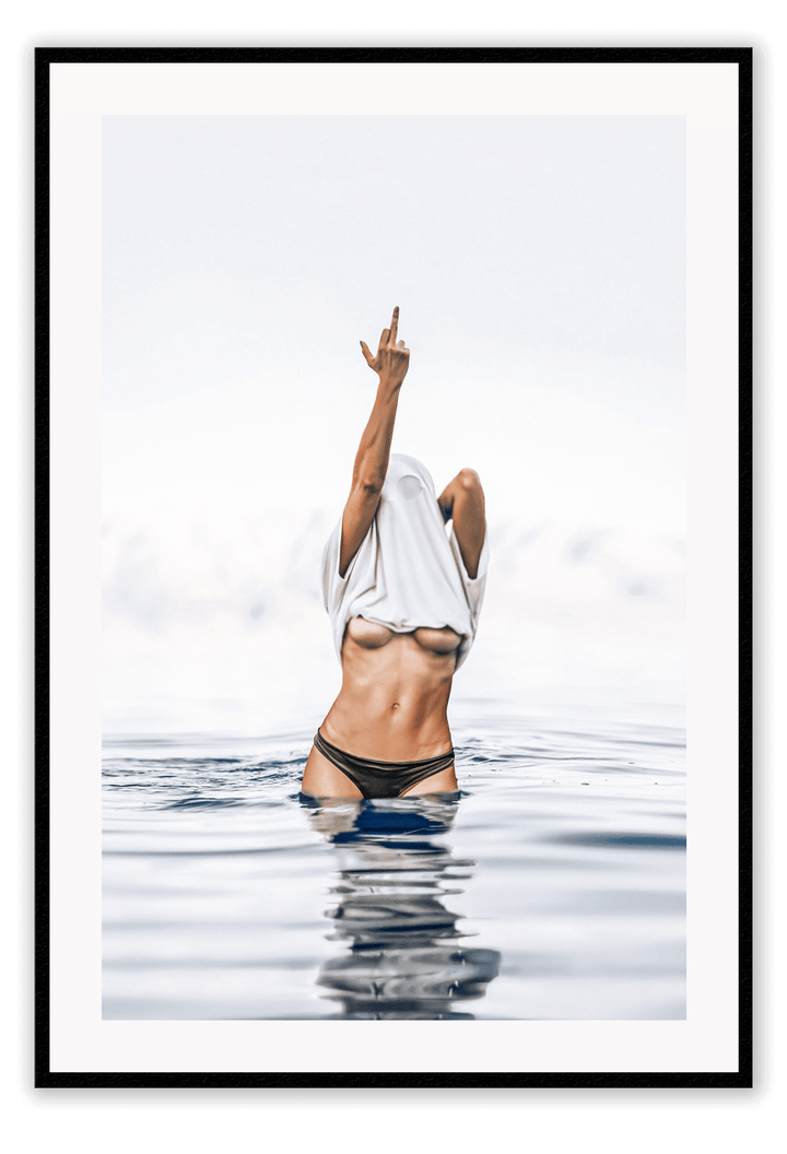 Person in black bikini standing in water with a white towel over their head, against a light gray sky.