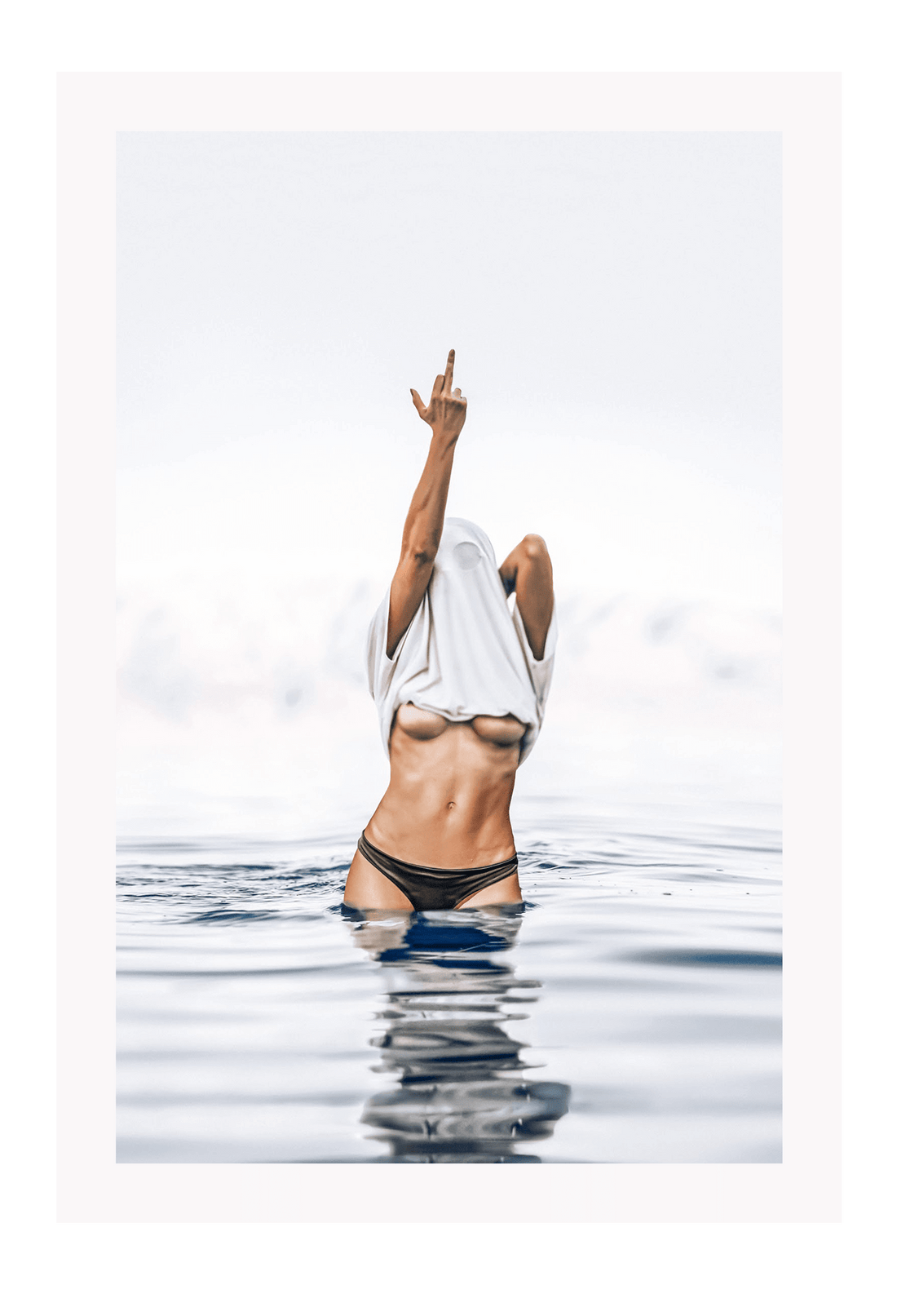 Person in black bikini standing in water with a white towel over their head.