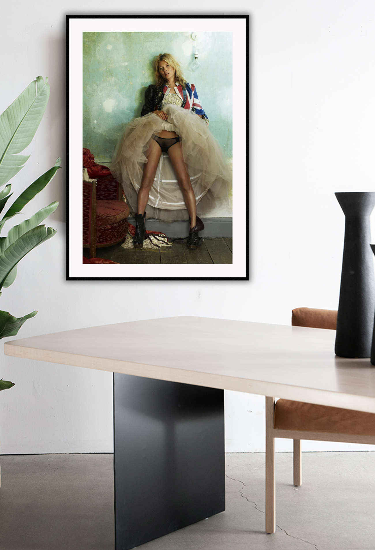 Fashion photography print featuring kate moss in a union jack jacket and hoop skirt lifing it up on a green wall background. Hanging on white wall in office setting.