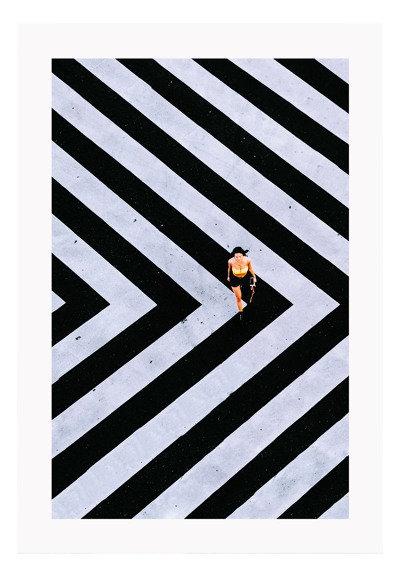 An urban wall art with an aerial view of a lady walking on black and white street crossing stripes