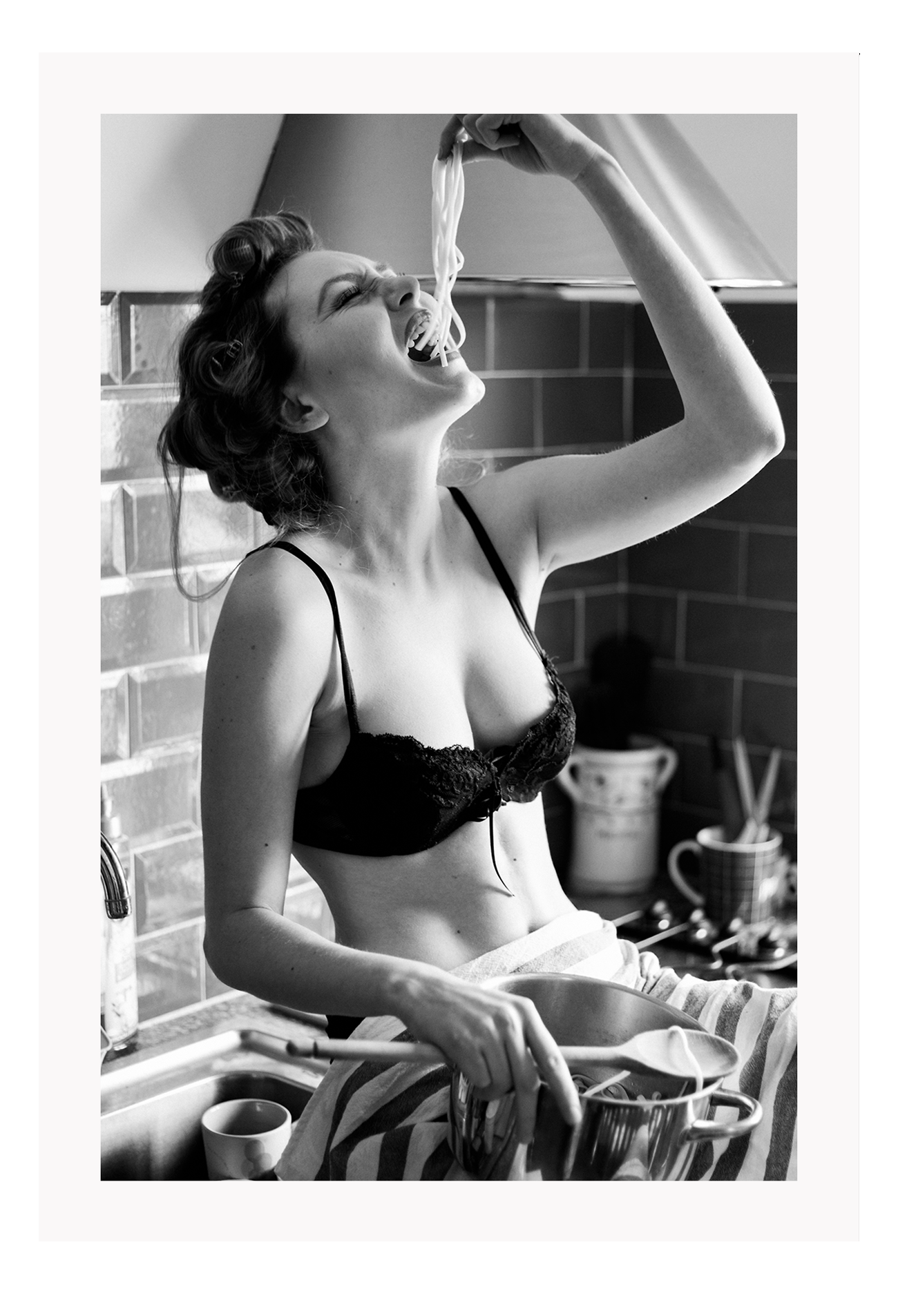 A black and white fashion wall art with a sexy lady in black lingerie eating pasta on the kitchen bench.