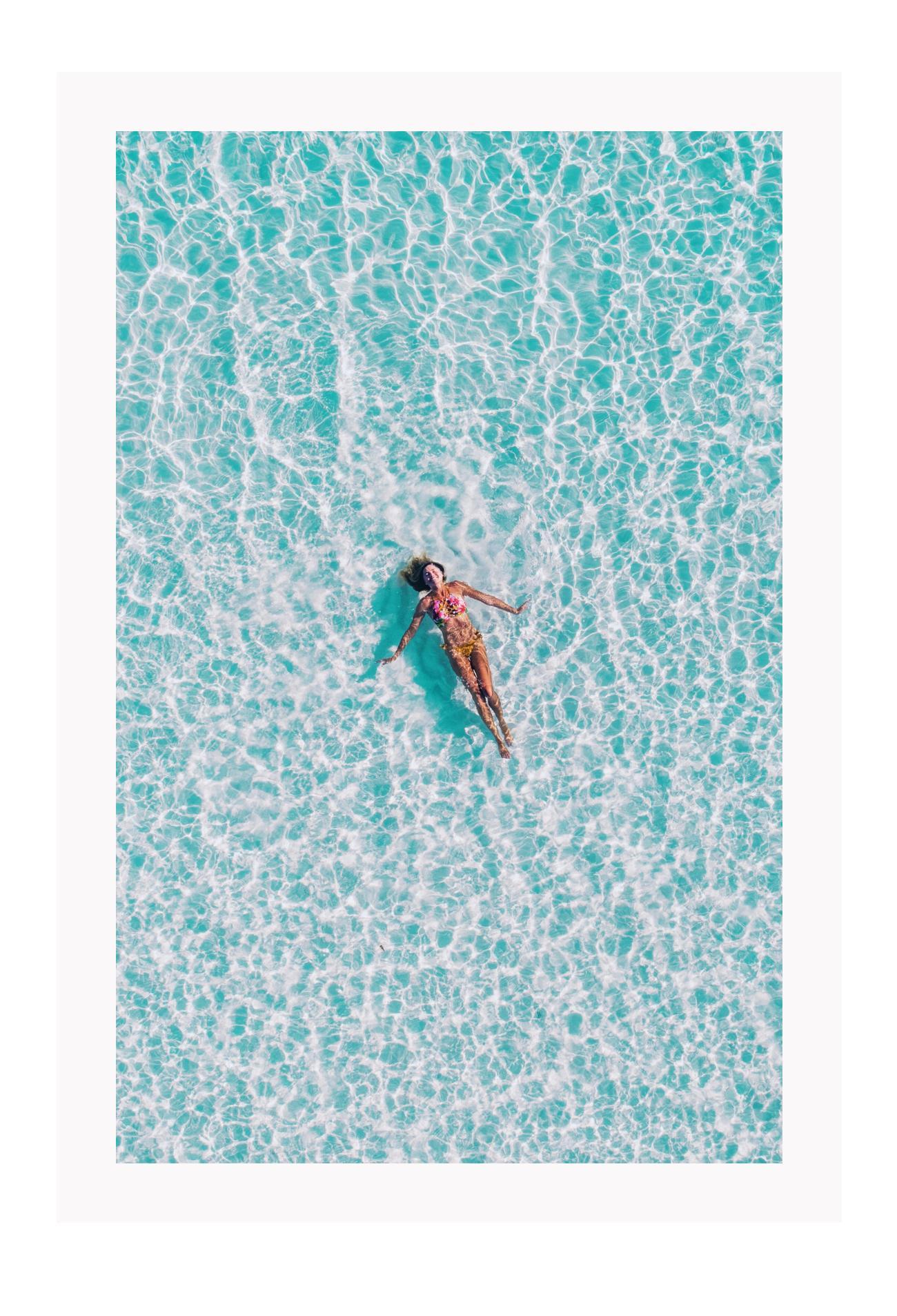 A framed print depicting a person swimming in a turquoise ocean, with a high quality custom frame.