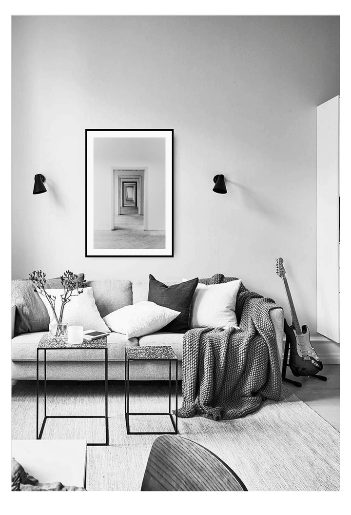 Black and white photo of room with wall art and lounge with cushions and guitar.