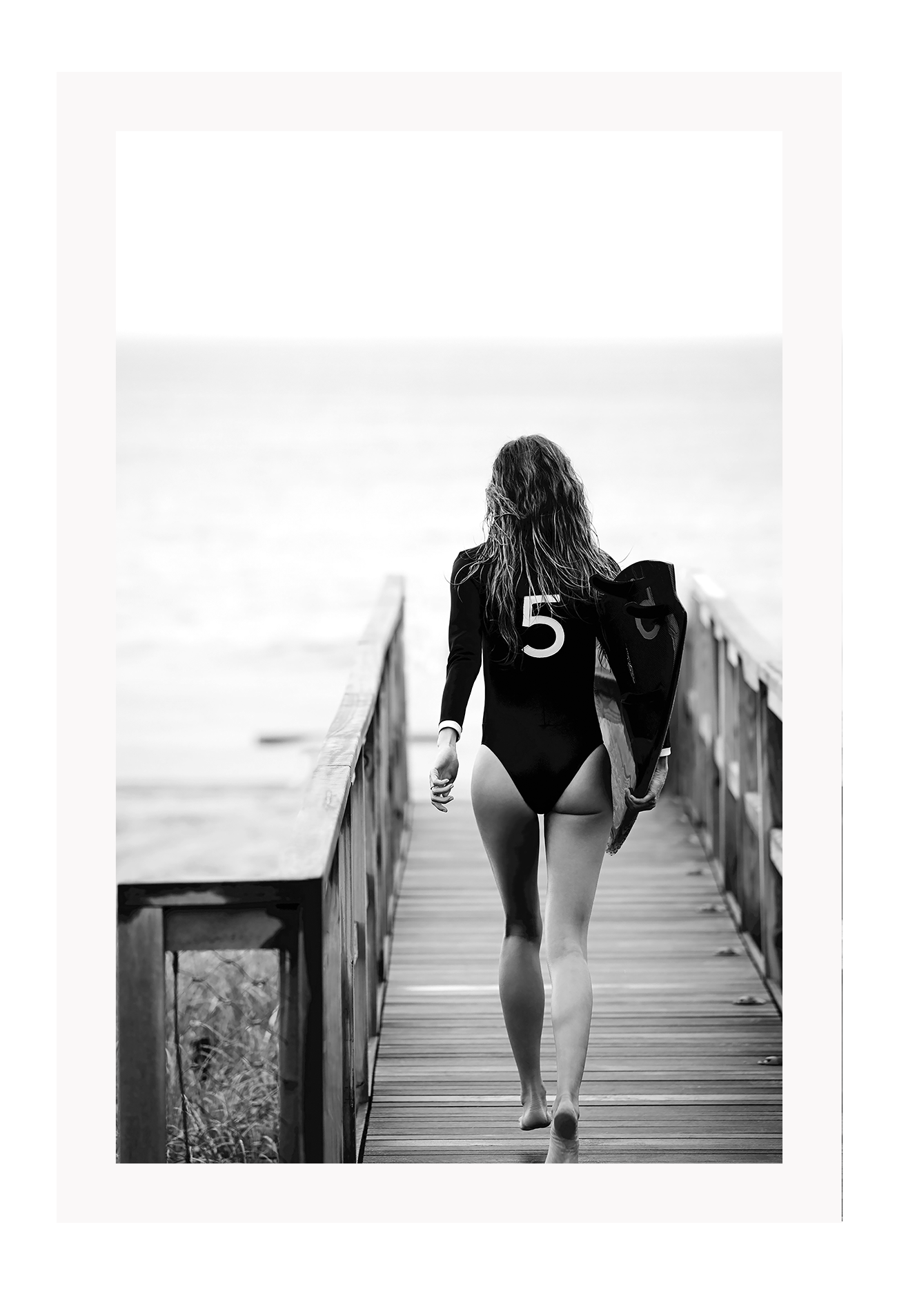A black and white fashion wall art with fashion model Gisele Bunchen holding Chanel N5 surf board.