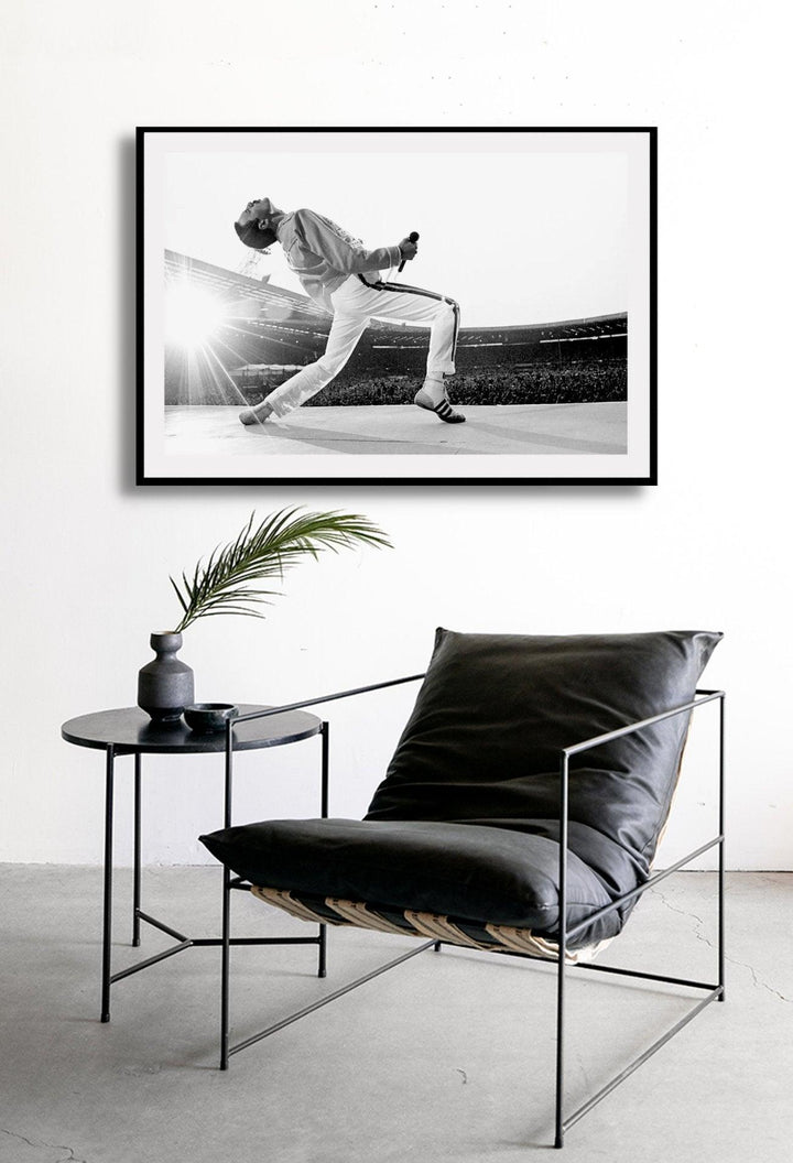A framed black and white photograph of Freddie Mercury in a dynamic pose, mounted in a matte black frame.