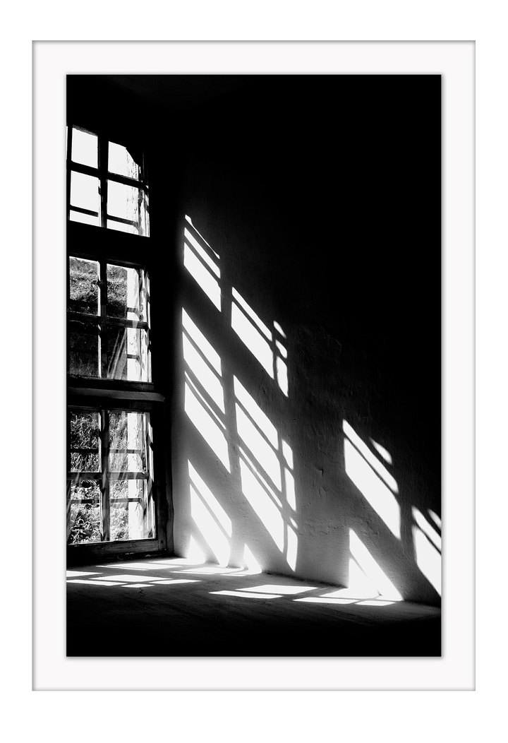 A black and white wall art with sunlight penetrating through big windows casting window shadows and creating high contrast.  